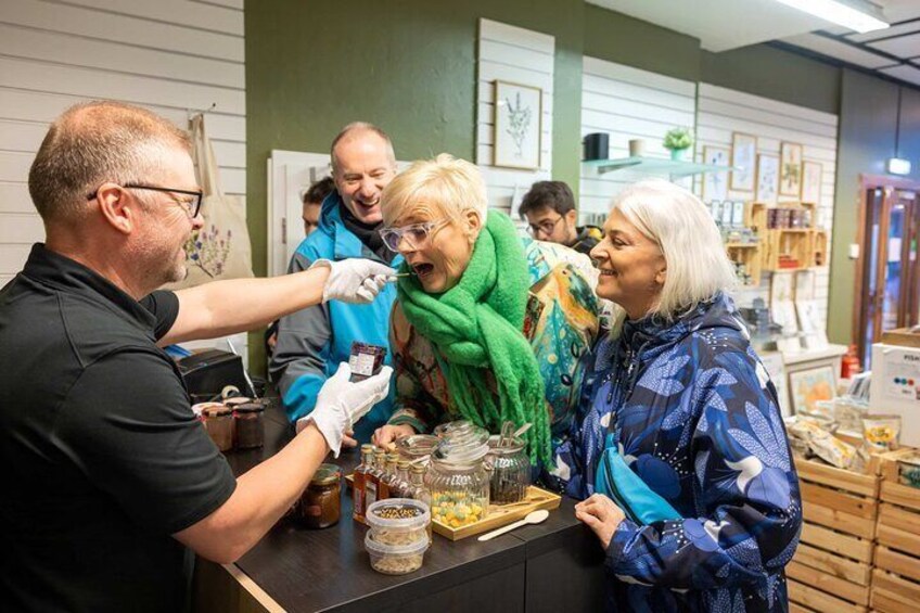 Une personne qui sert de la nourriture au comptoir, où sont exposés divers articles, comme des bocaux et des récipients. 3