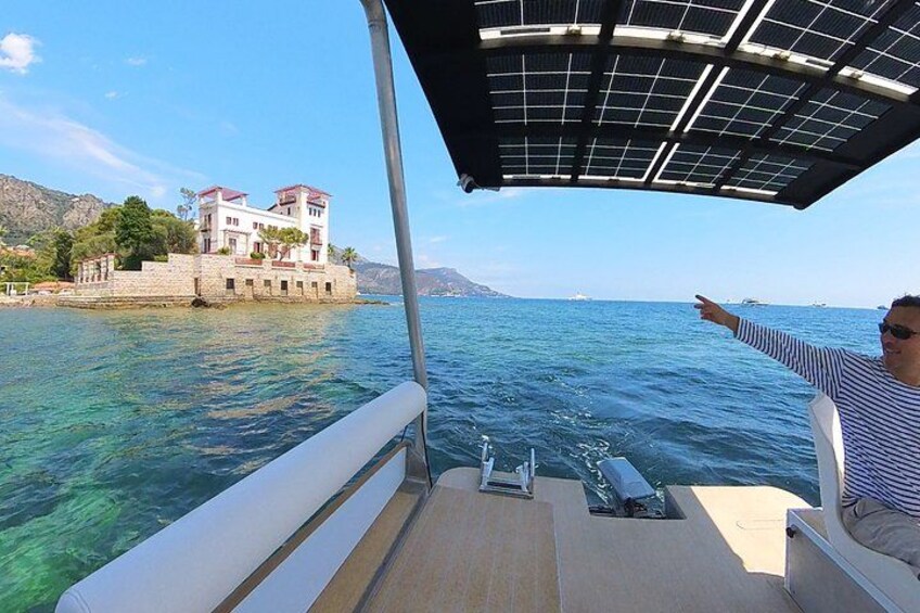 A boat with a person pointing towards a coastal building. 3