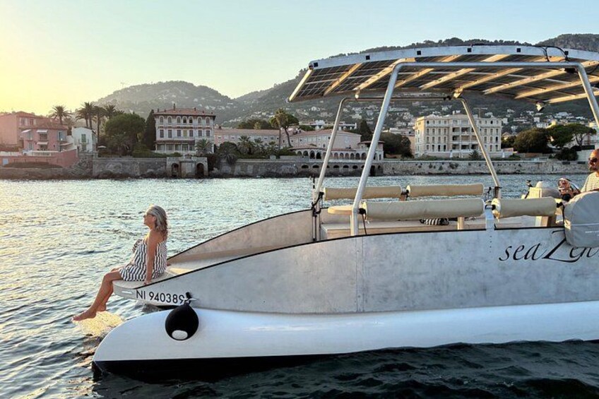 A boat with a person sitting on the bow, a covered area, and buildings in the background. 5