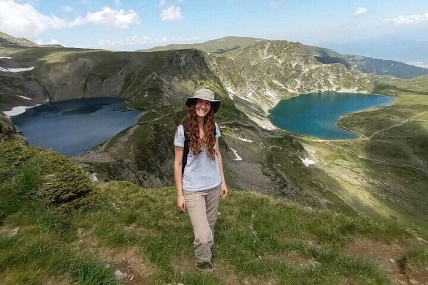 A person standing on a grassy hill overlooking a valley with two lakes. 2