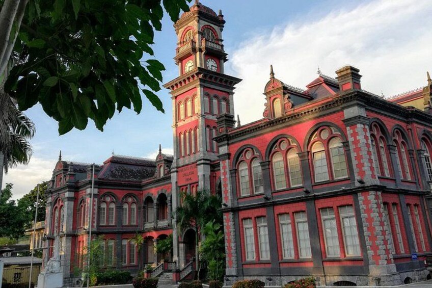 A historic building with red and grey architecture, featuring arched windows and a clock tower. 3