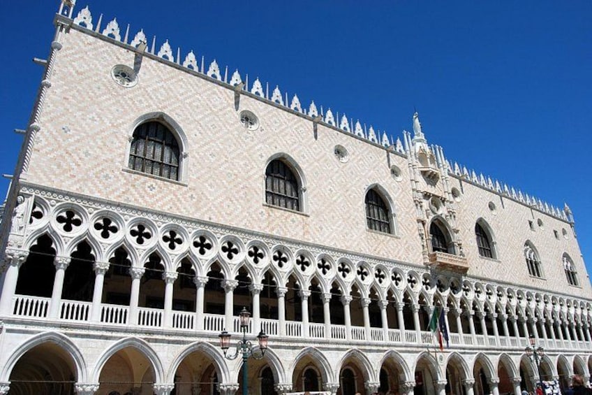 A historic building with a tiled facade, arched windows, and a series of arches along the ground floor. 5