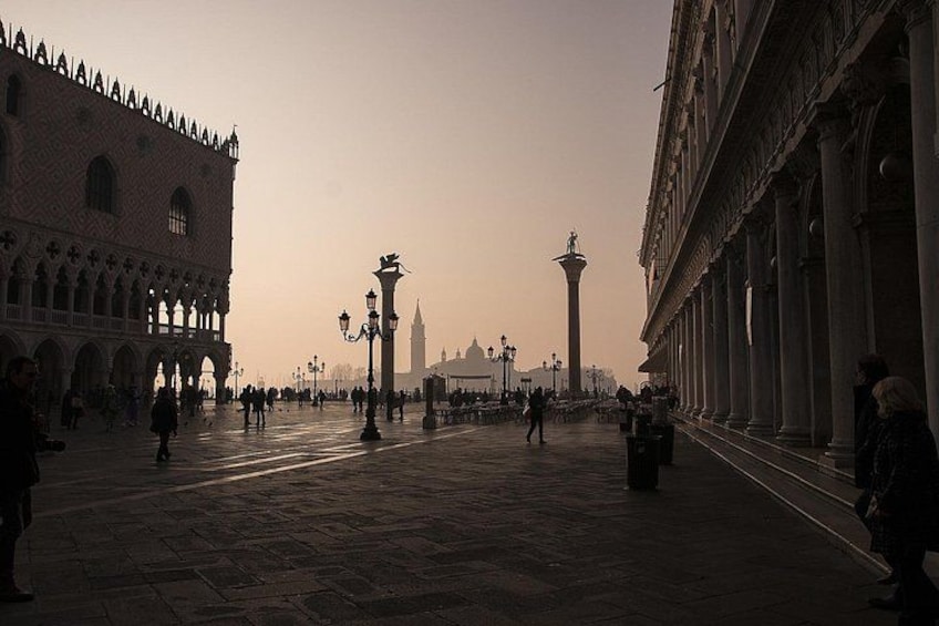 A wide, open square with historical buildings, a prominent tower, and a statue. 2
