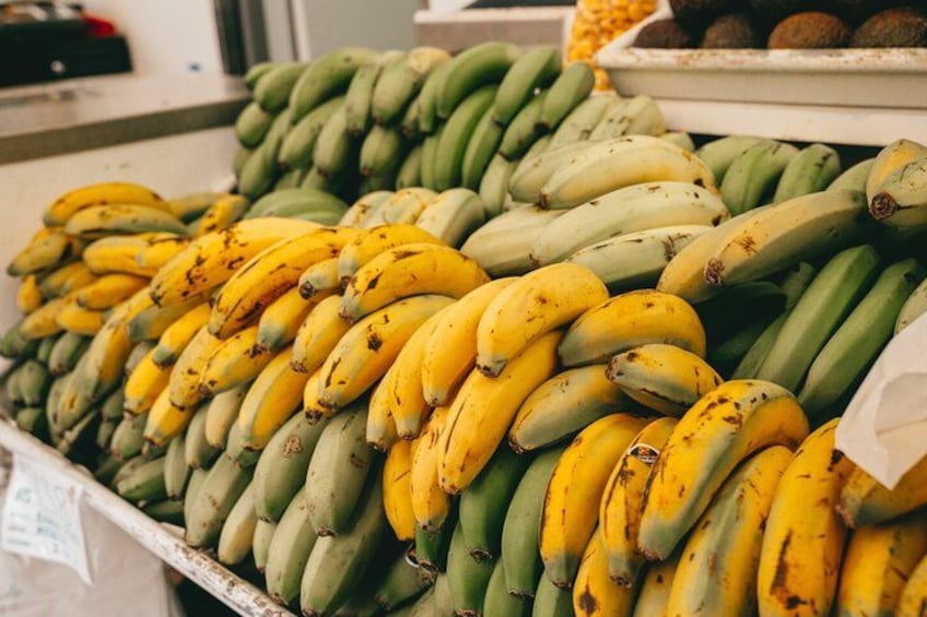Een presentatie van bananen in verschillende rijpingsstadia, van groen tot geel, gerangschikt in een marktomgeving. 3