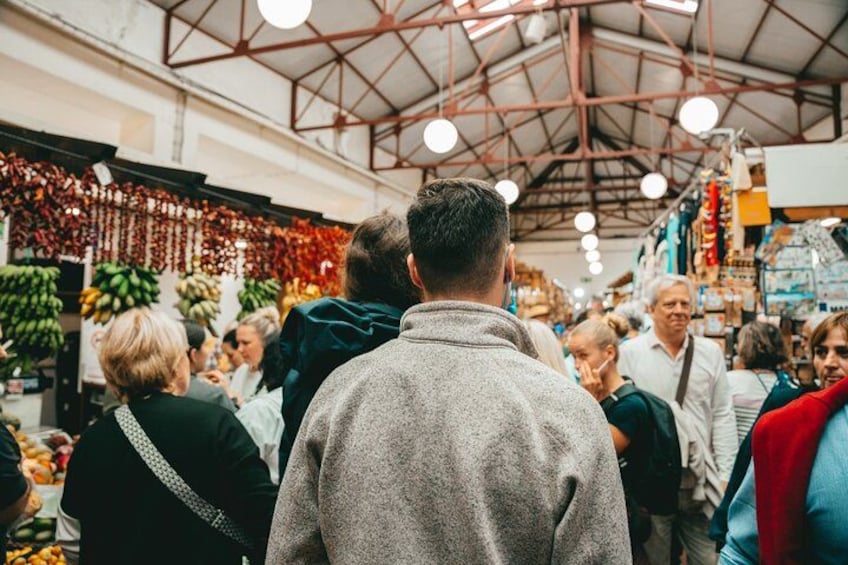 Een overdekte markt waar mensen rondkijken en winkelen. 4