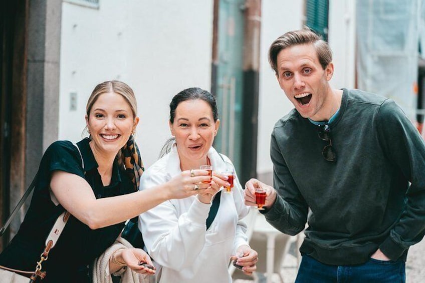 Three people toasting with drinks in an urban street setting. 4