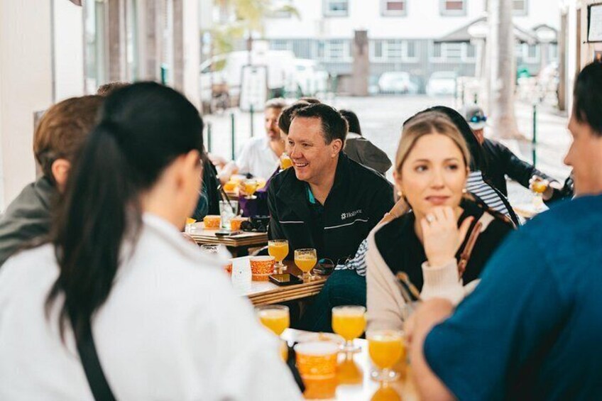 A group of people sitting at a table with drinks, engaged in conversation. 2