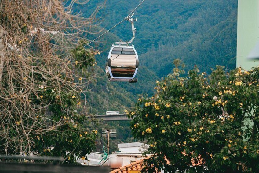 A cable car suspended over a mountainous landscape with greenery and buildings below. 5