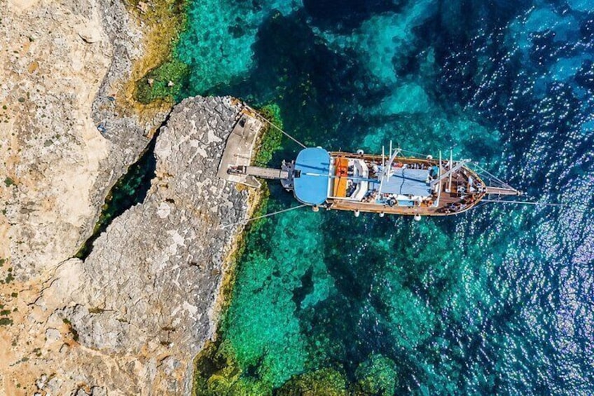 Un barco anclado cerca de una costa rocosa con aguas turquesas cristalinas. 1