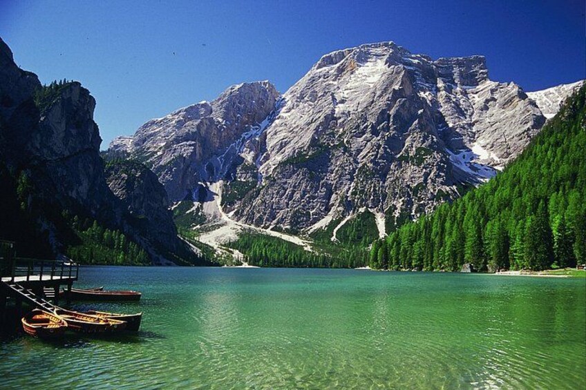 A mountain lake with clear water, boats, and a cabin. 1