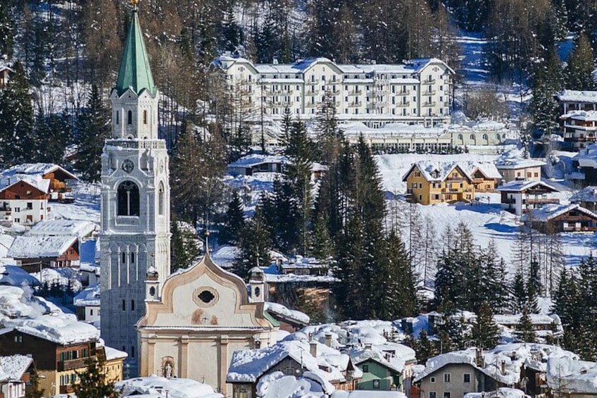 A snow-covered town with a church tower, residential buildings, and a large hotel. 5