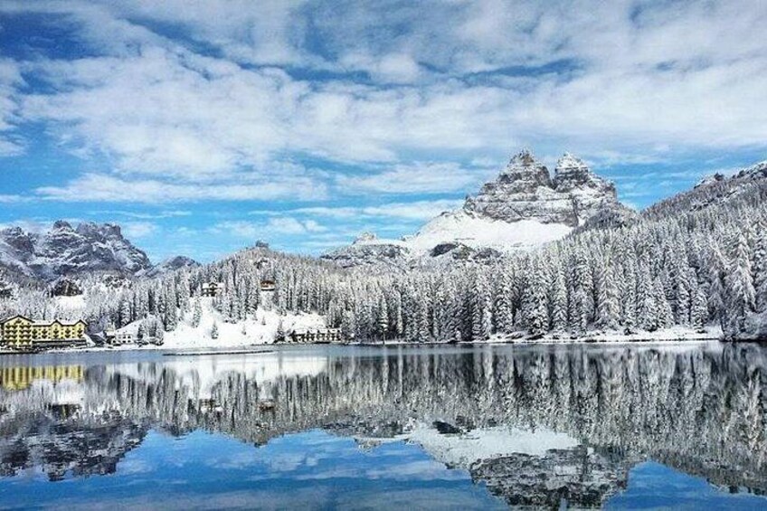 A snow-covered mountain range, a lake, and a building with a yellow facade. 4