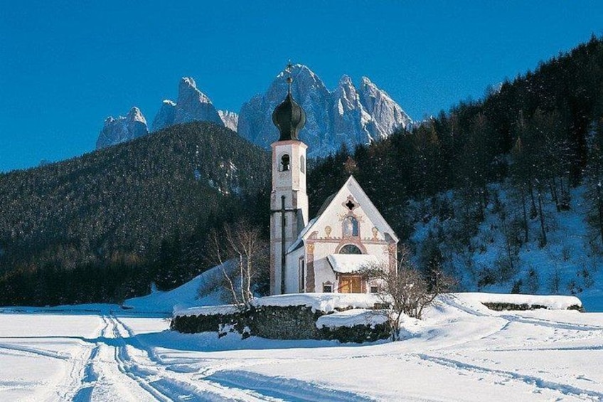 Een met sneeuw bedekte kerk met een klokkentoren en een berg op de achtergrond. 2