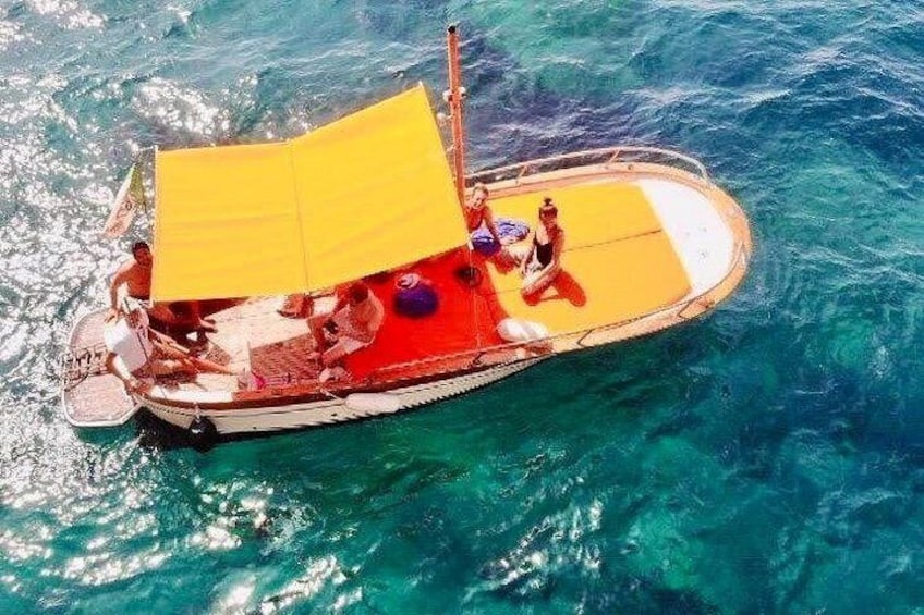 Een boot met een geel dak, mensen aan boord en helderblauw water. 3