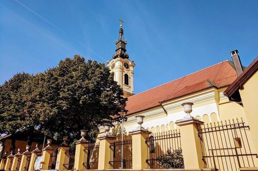 A church with a tall bell tower and a fence with decorative pillars. 3