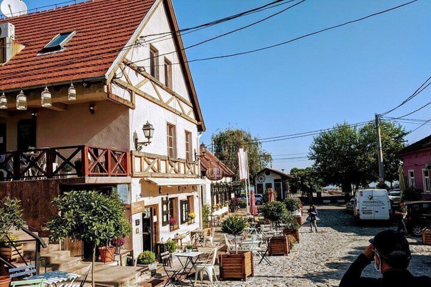 A traditional half-timbered building with outdoor seating, a gravel street, and a parked van. 5