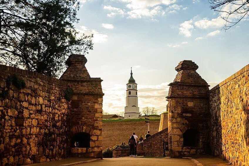 A historical stone wall with a bell tower in the background. 1