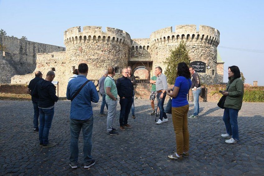 A group of people standing in front of a historic stone castle with a round tower. 2
