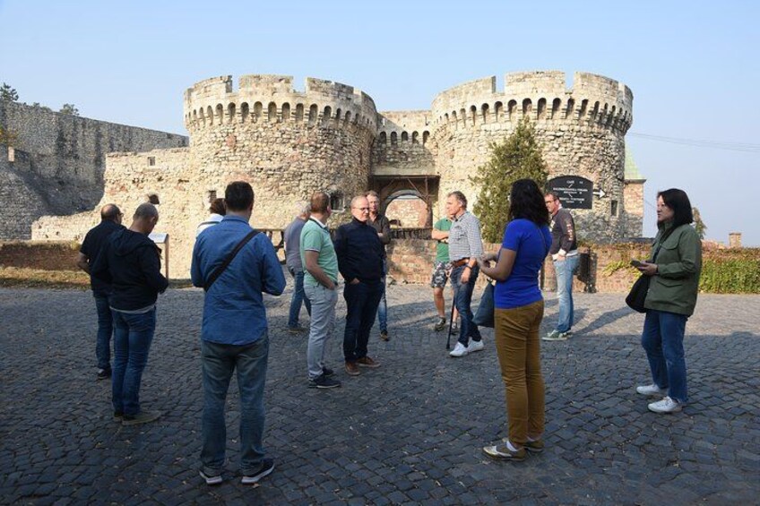A group of people standing in front of a historic stone castle with a round tower. 2