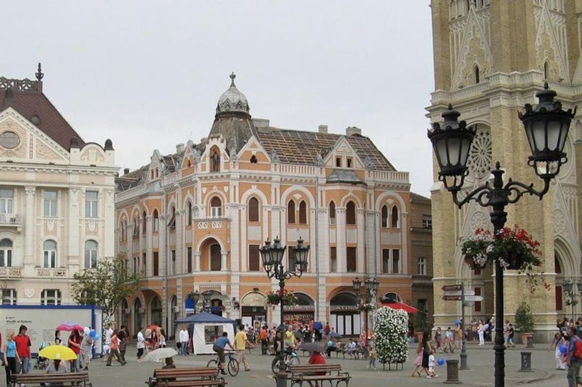 Un bâtiment historique à l’architecture riche et ornée, une place publique avec des bancs et un beffroi. 4