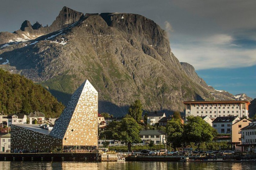 A mountain, a pyramid-shaped building, and a town with buildings along a waterfront. 1
