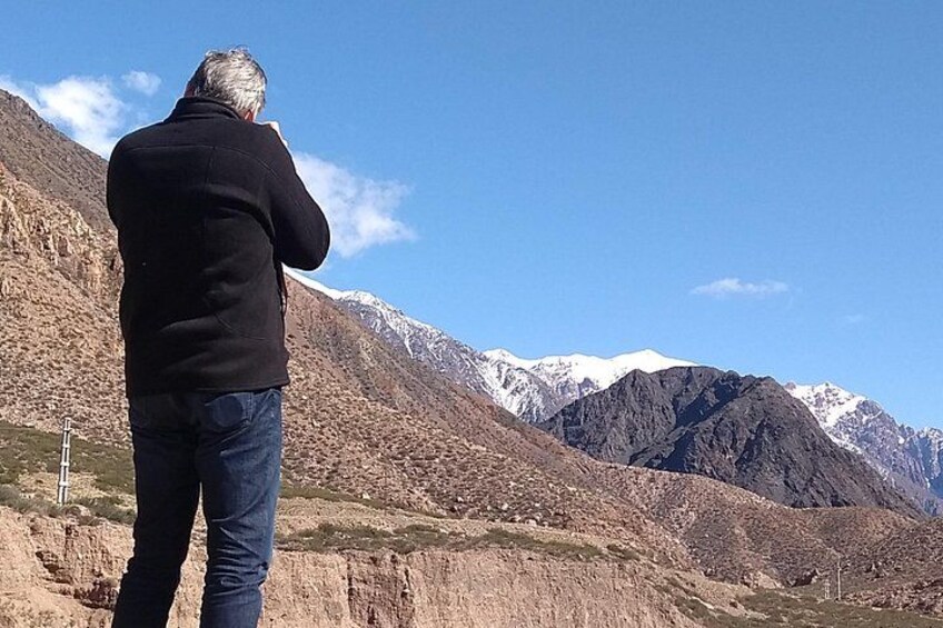 A person standing on a mountain ridge, overlooking a range of snow-capped mountains under a clear sky. 5