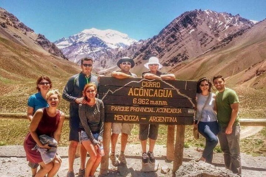 A group of people standing in front of a sign with text. 2