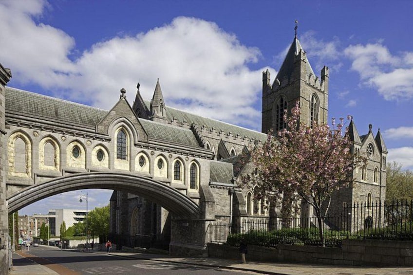 A stone bridge, a church with a tall tower, and a blooming tree. 1