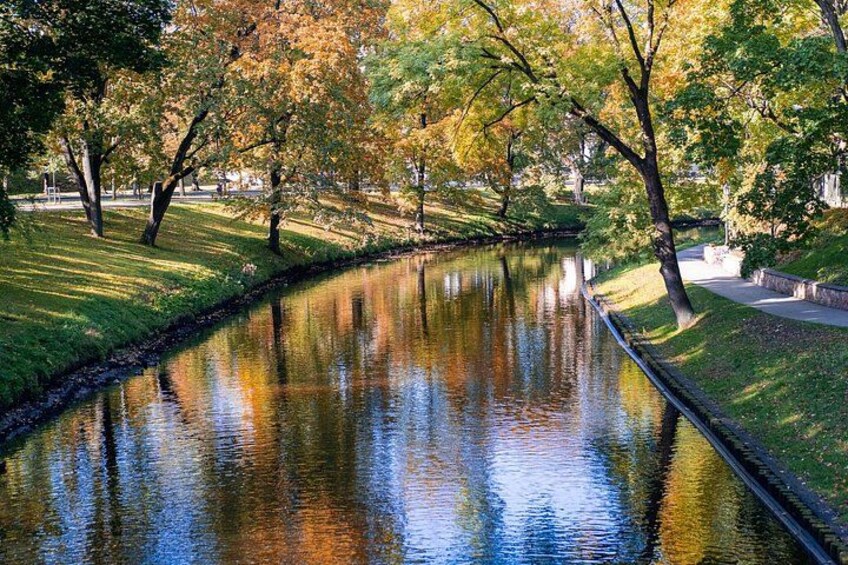 Een rustige rivier met bomen die zich in het water spiegelen, omringd door gras en een pad. 2