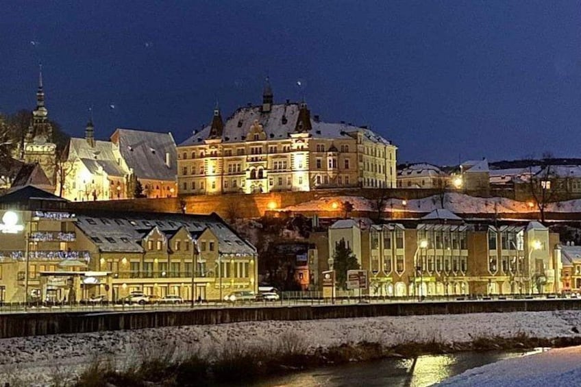 Un paisaje urbano nevado de noche, con edificios iluminados y un río en primer plano. 5