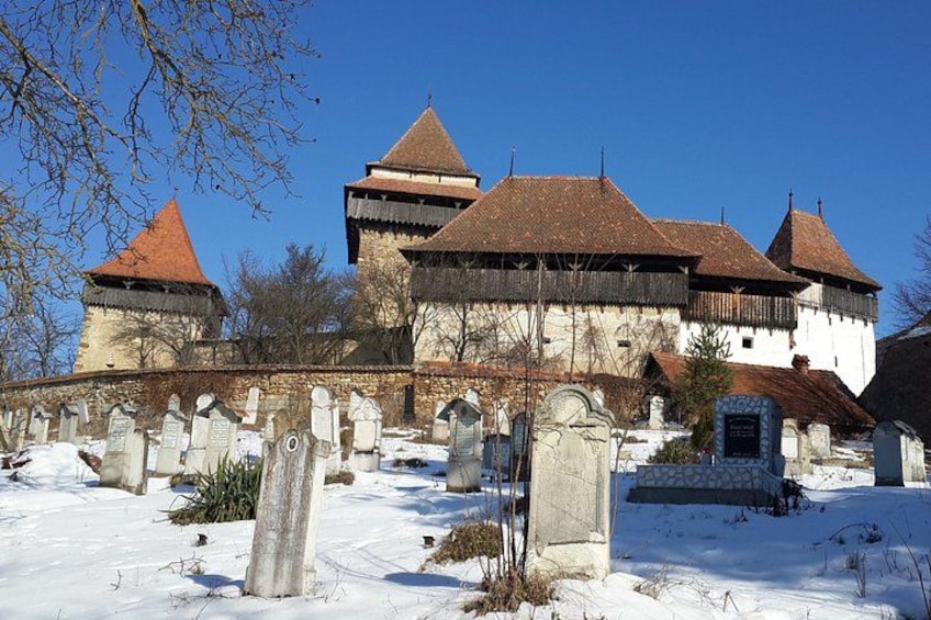 Un bâtiment historique doté de plusieurs tours, avec un cimetière en premier plan. 1