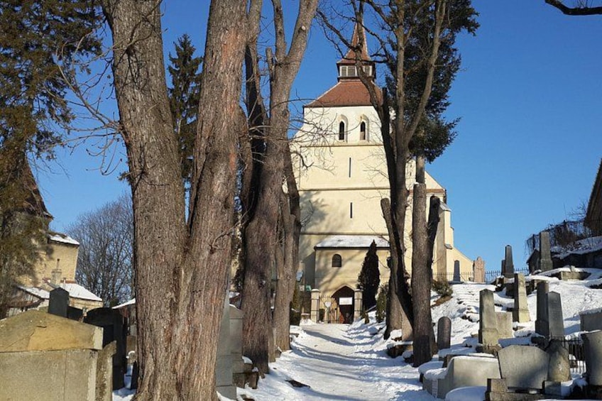 Une église avec un toit rouge, entourée d’un paysage enneigé et d’arbres sans feuilles. 5