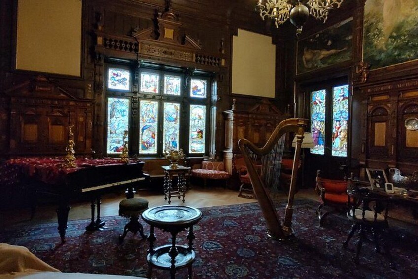 A grand room with a harp, a piano, and stained glass windows. 2