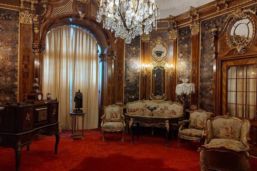 An opulent room with ornate furniture, a chandelier, and a large mirror. 4