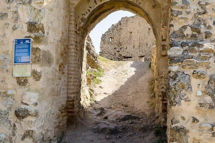 Un arc en pierre mène à un site historique, avec des ruines en arrière-plan. 3