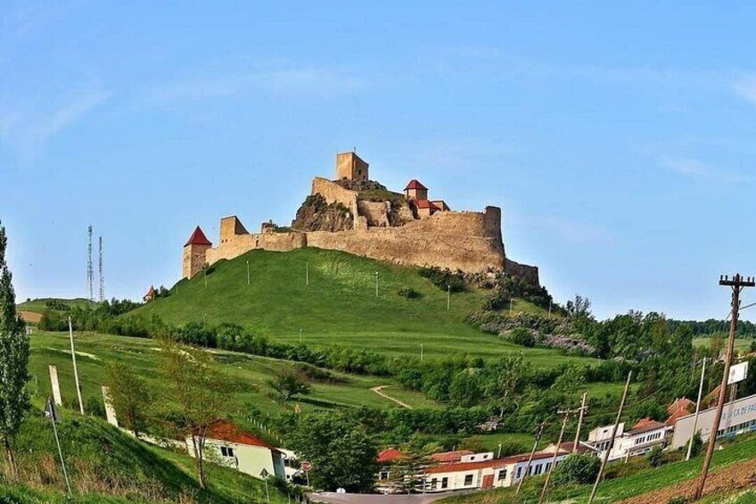 Un château historique perché sur une colline, entouré de verdure, avec un petit village en contrebas. 5