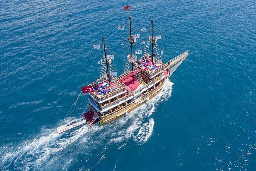 Un grand bateau à plusieurs ponts, arborant de nombreux pavillons, naviguant sur un océan bleu. 1