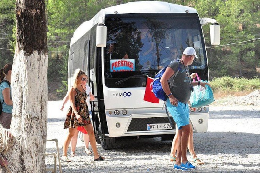 Un autobús turístico blanco con la leyenda 'PRESTIGE' en la carrocería, estacionado en un camino de grava. 4