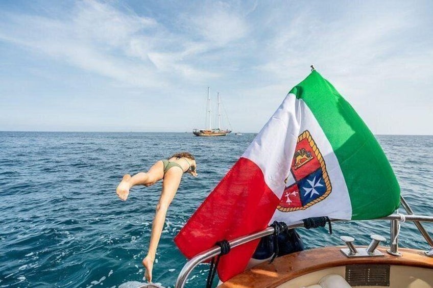 Una persona se sumerge en el océano desde un barco, con una bandera al frente. 2