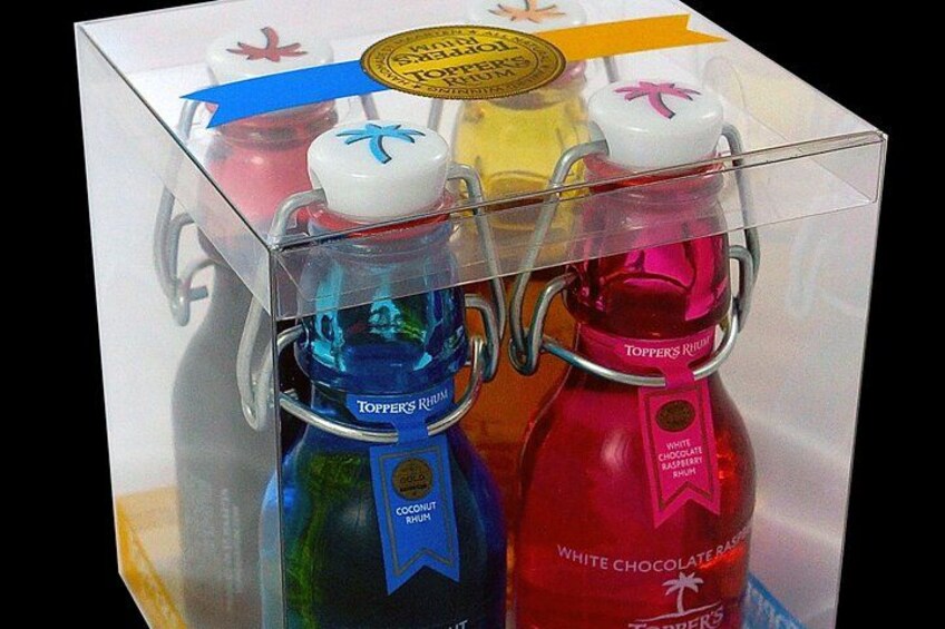 Una caja que contiene dos botellas de ron Toppers, una azul y otra roja, con etiquetas que indican sabores como ron con coco y frambuesa con chocolate blanco. 5