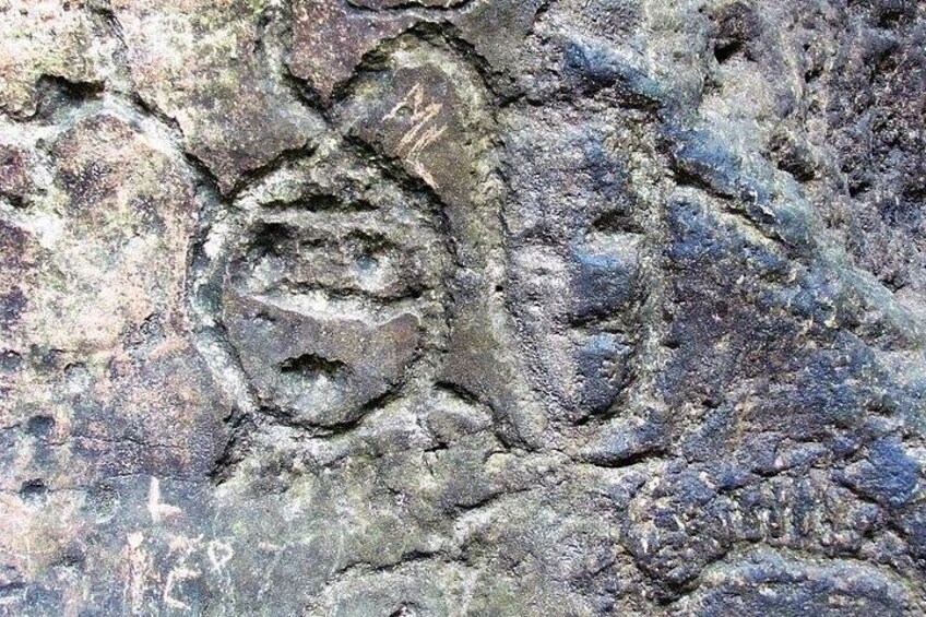 A close-up of a rock surface with a carved face. 4