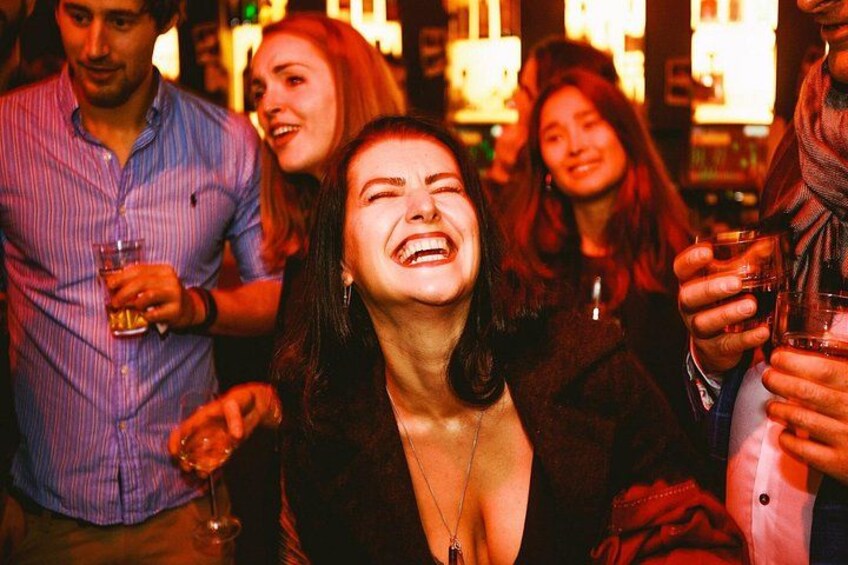 Un gruppo di persone in un ambiente conviviale, forse un bar o una discoteca, alcune delle quali sorseggiano bevande. 2