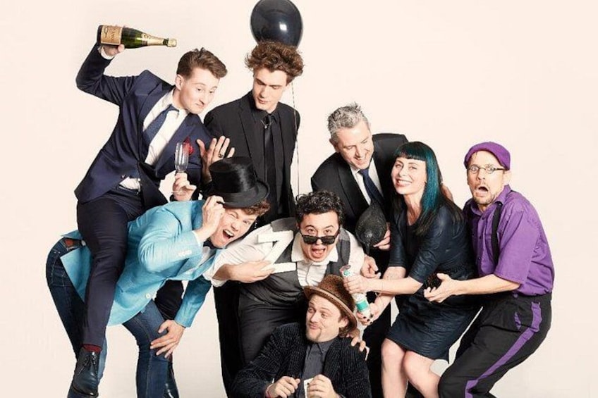 Un gruppo di persone in diverse pose, alcune che tengono bottiglie di champagne. 1