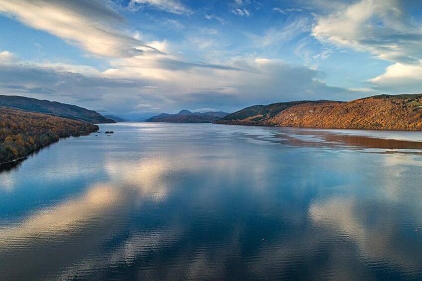 A calm lake surrounded by hills with autumn foliage. 1