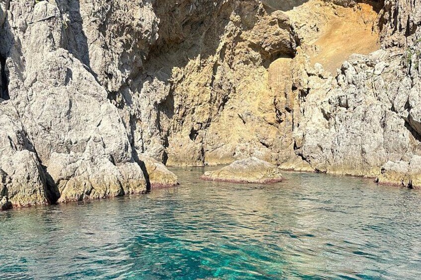 Eine zerklüftete Küstenlinie mit klarem türkisfarbenem Wasser. 2