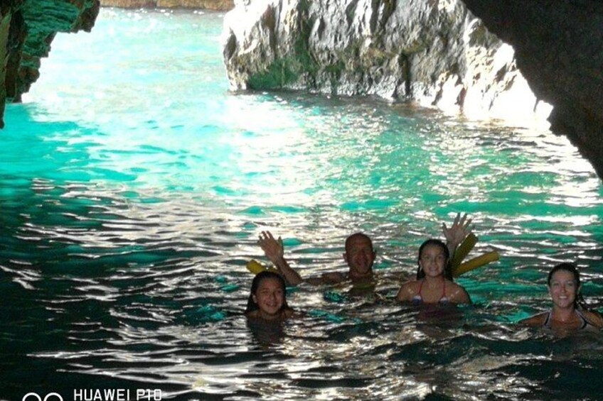 Eine Gruppe von Menschen schwimmt in einem türkisfarbenen Pool vor einer Felsküste. 3