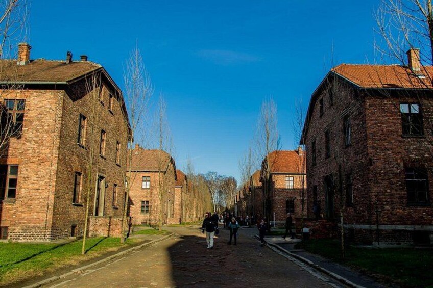 A street lined with brick buildings, a clear blue sky, and a few pedestrians. 2