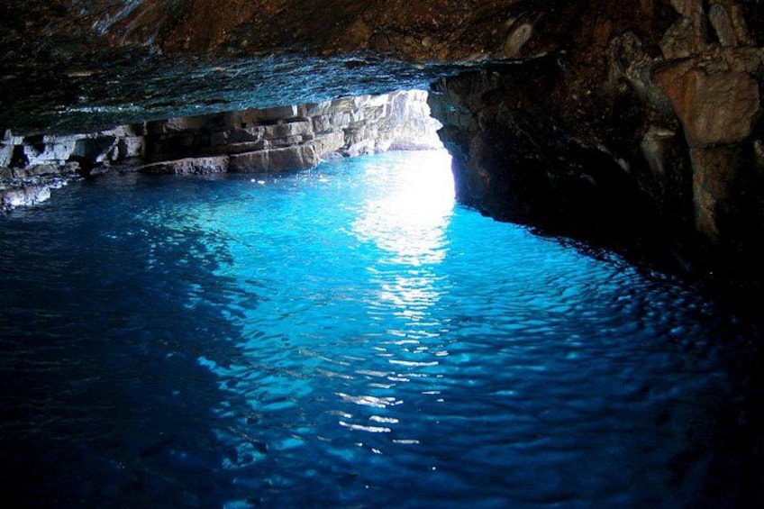 Una cueva con un estanque de agua azul cristalina que refleja la luz. 4