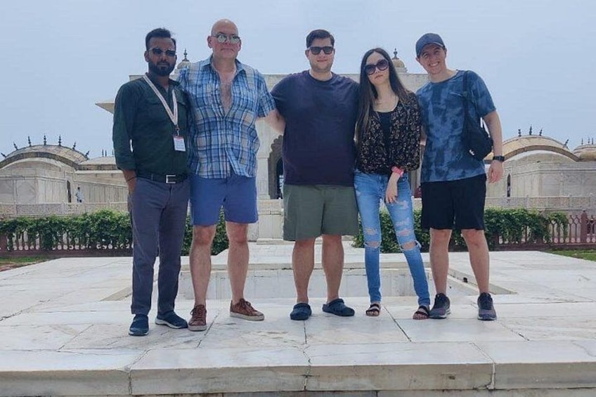A group of people standing on a stone platform with a historical building in the background. 2