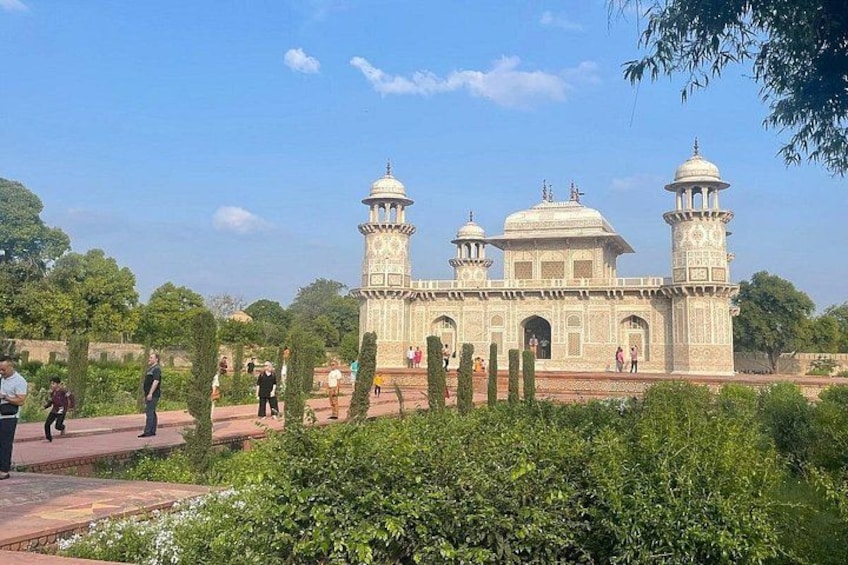 A large, white, domed building with two towers, surrounded by greenery and people. 4